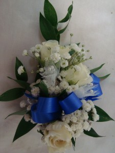Most Popular wrist corsage with    (CO) 3 sweetheart roses and includes real greens and baby's breath. Call to let us know what ribbon you would like