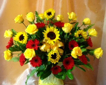 Bright shades of yellows and reds  (E) arranged...roses, gerberas, sunflowers.