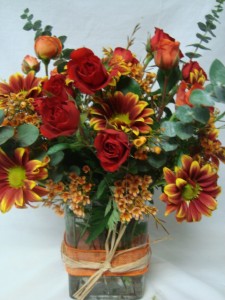 Orange and Red spray Roses with fall  (F) varigated daisies and wax flower all arranged in a rectangular vase!