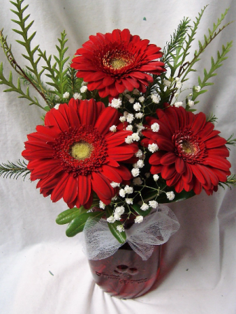 3 mini red gerbera daisies arranged in a  (E) mason jar...jar color may vary depending on stock