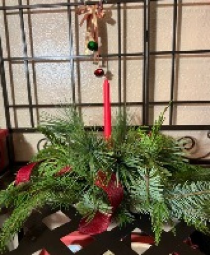 Round centerpiece  Fresh holiday greens with  a single  candle round