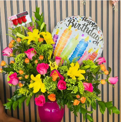 Sunrise Arrangement Arrangement in a vase made of hot pink roses, yellow lilys, orange mini spray roses, solidago, etc. * Ballon is included